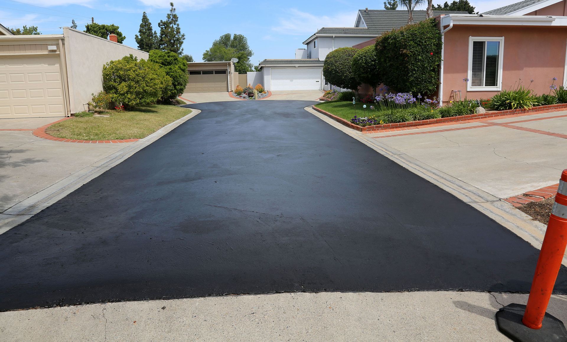 Newly paved black asphalt driveway leading up to a residential home